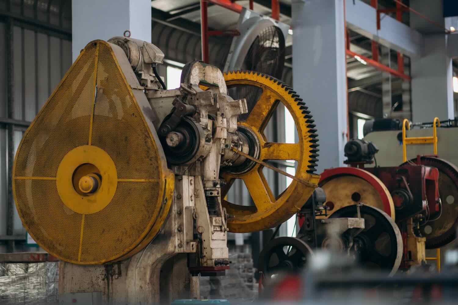A yellow and white machine with a yellow guard. The machine is old and rusty